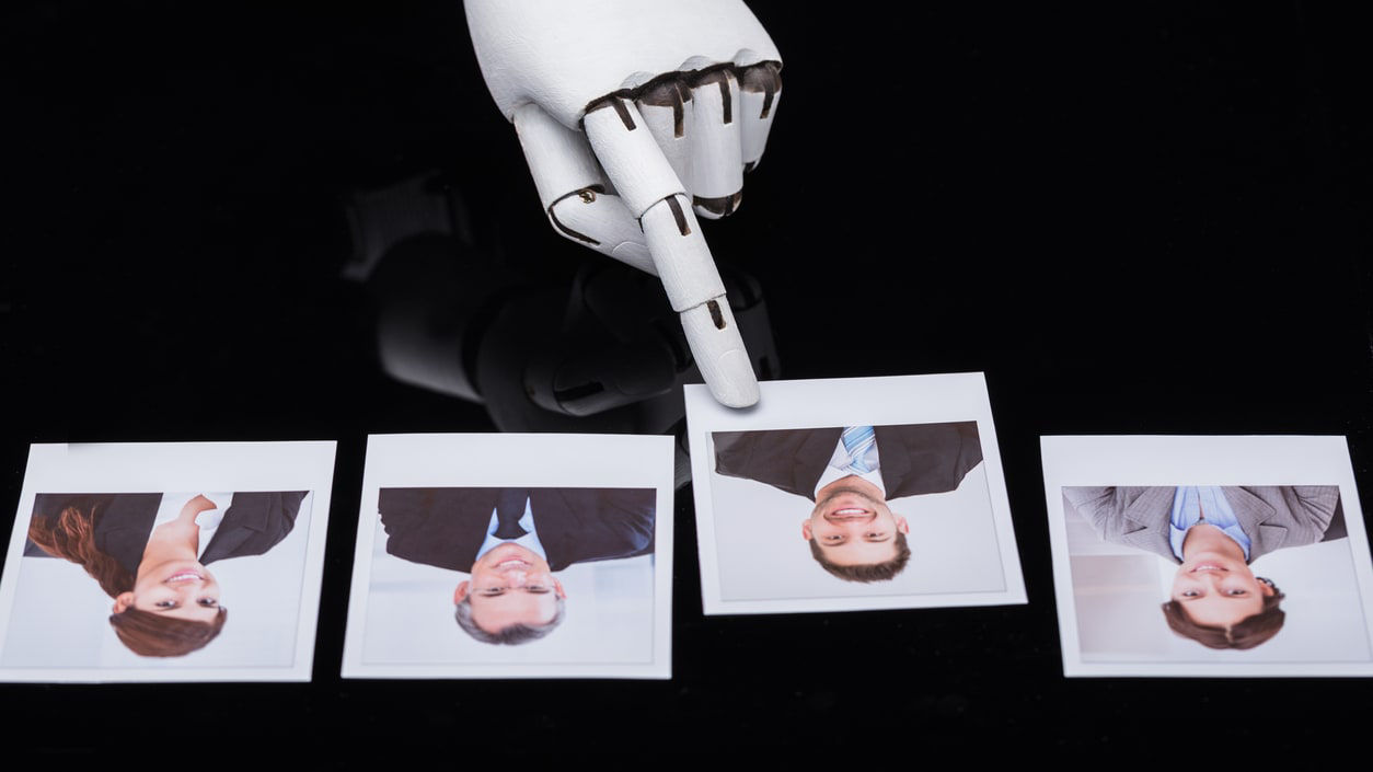 A robot is holding a photo of a man and a woman.