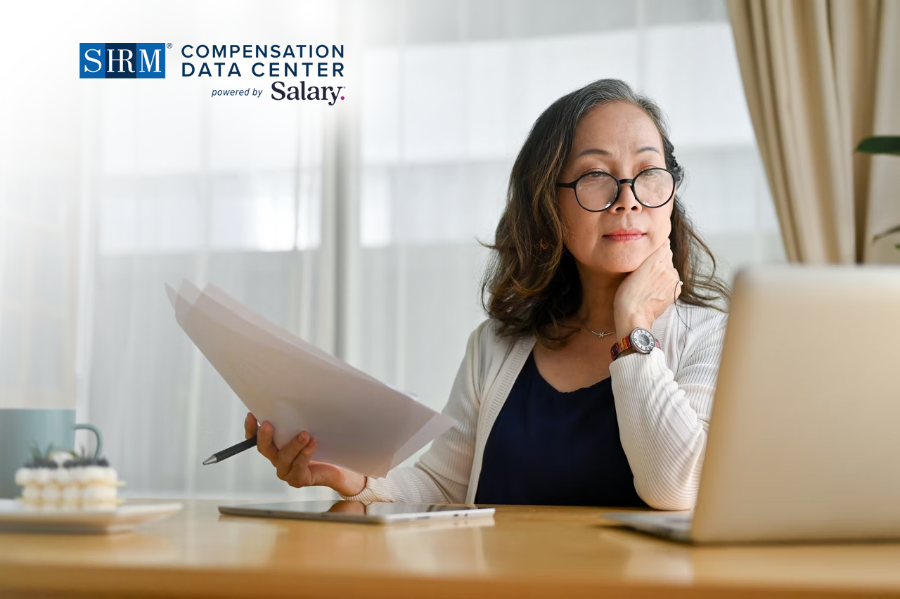Lady Analyzing in laptop and with papers and pen in her hand
