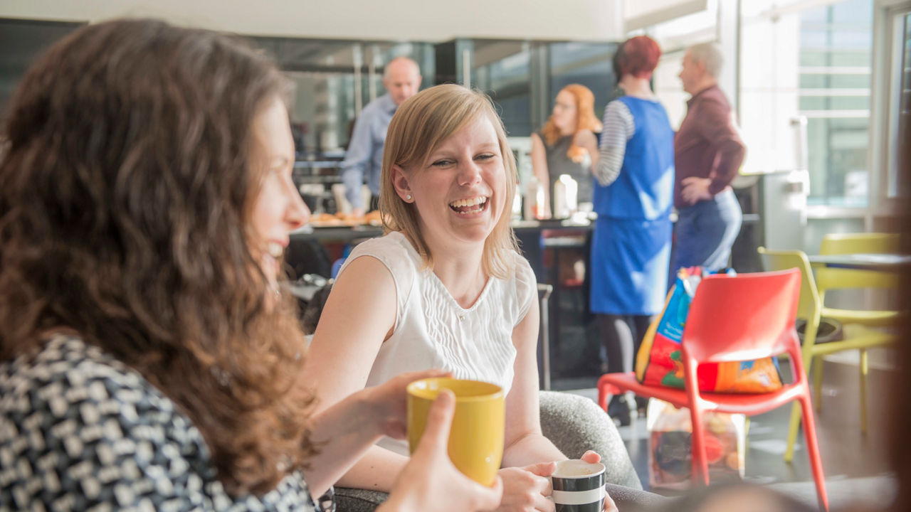 A group of women laughing in a coffee shop.