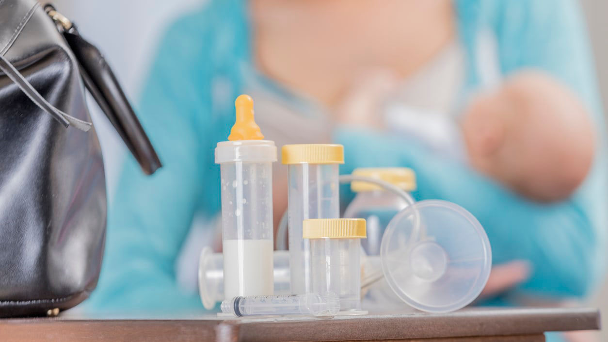 A woman with a baby in front of a bag.