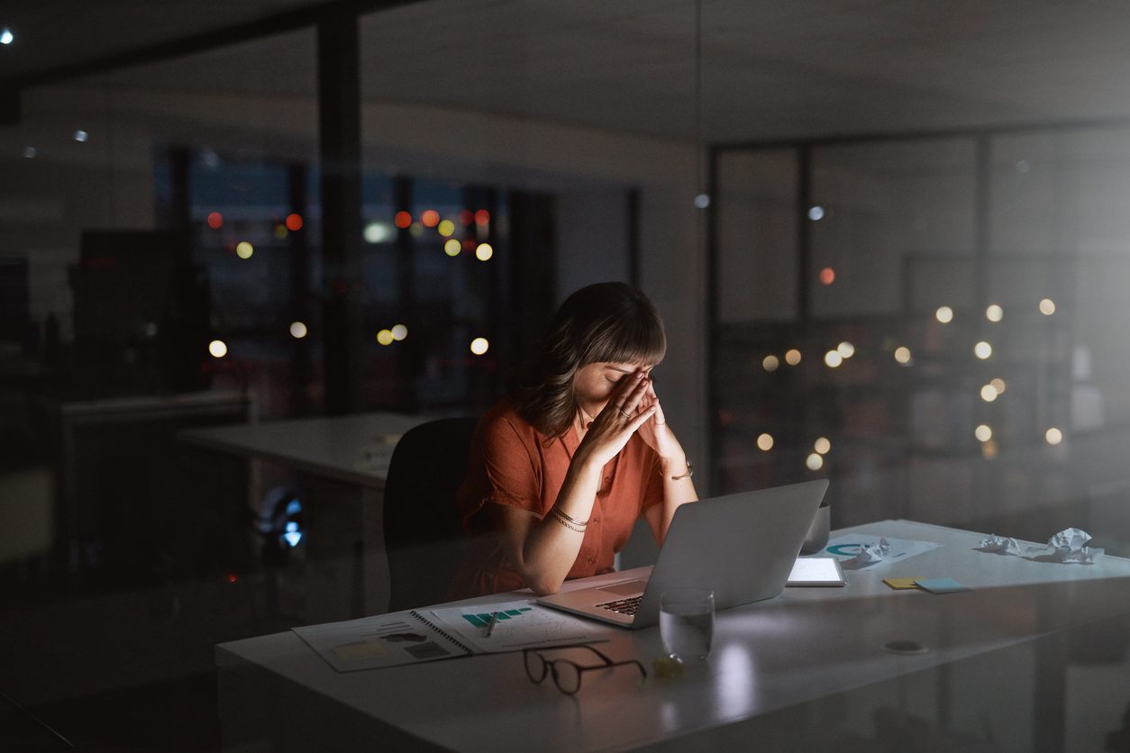 a woman working in an office late at night and looking overwhelmed