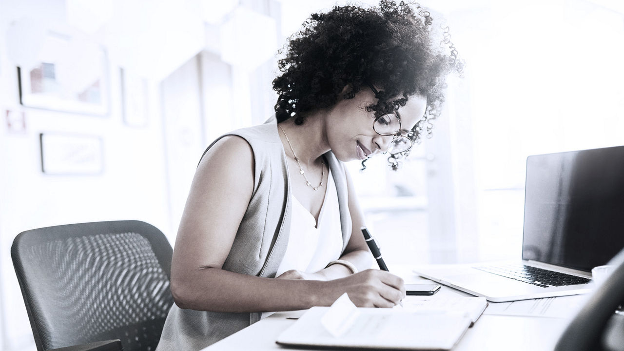 Female business executive sitting at a desk journaling.