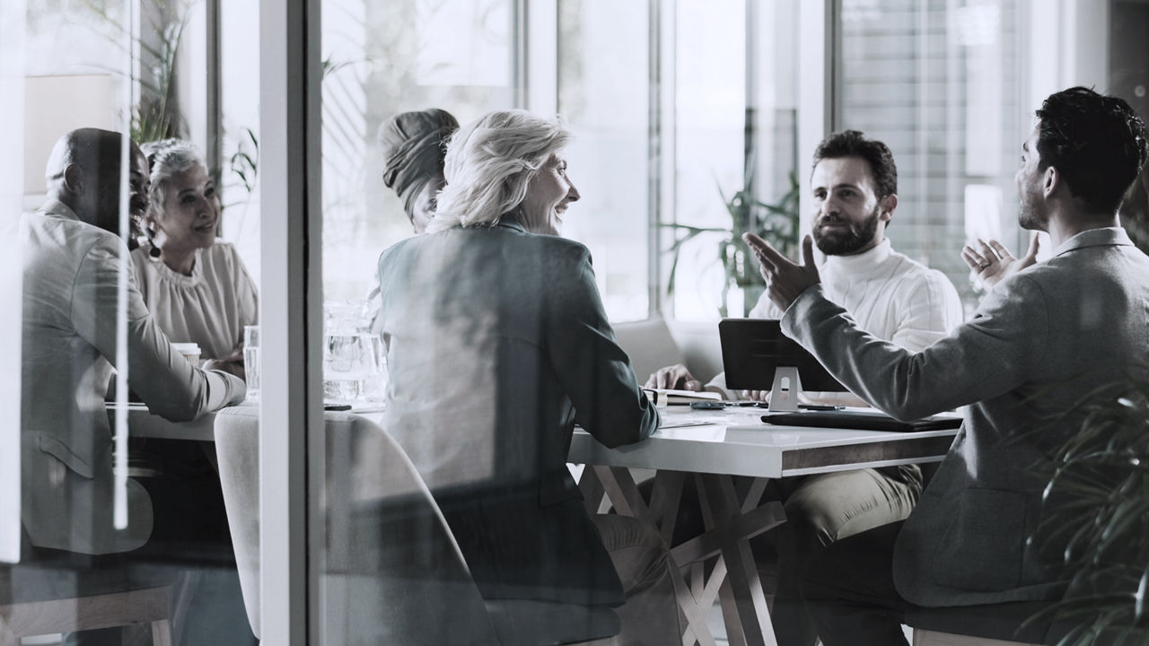 a view of multiple people sitting at a conference table in discussion
