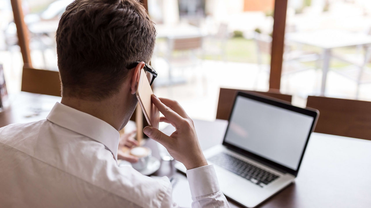 A man is talking on the phone while sitting at a table.