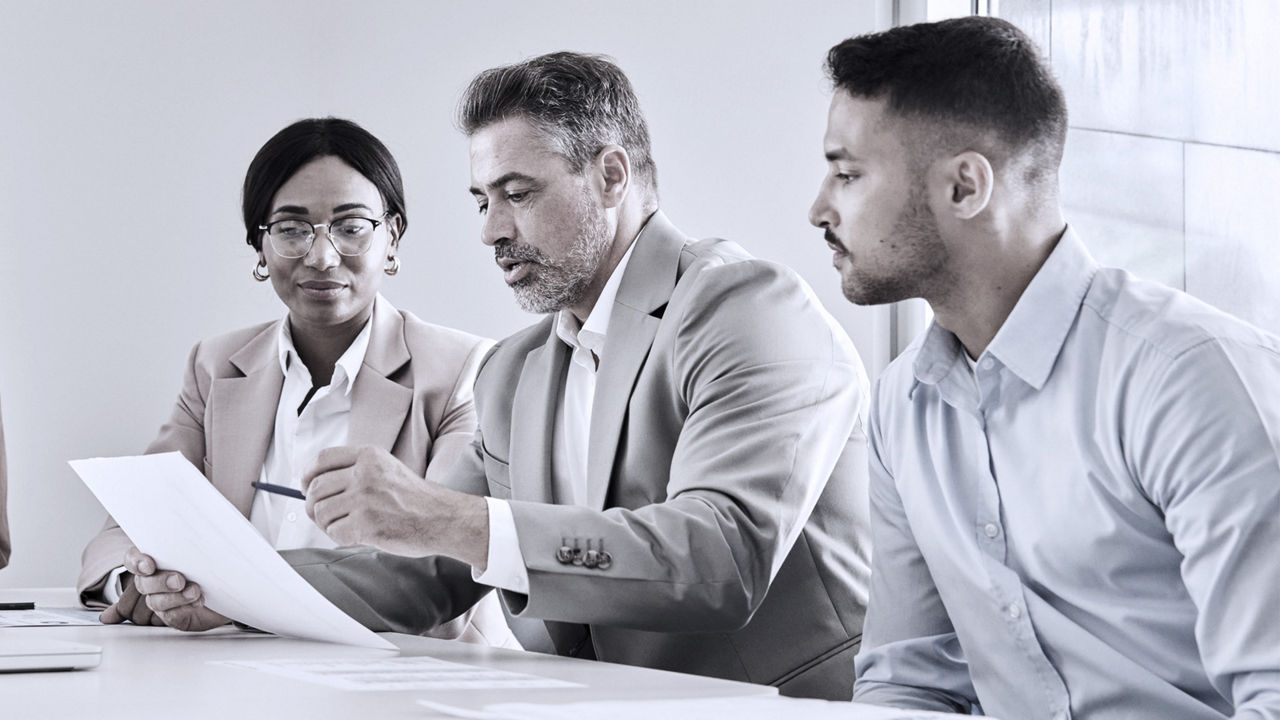 Three business leaders looking at a candidate's resume