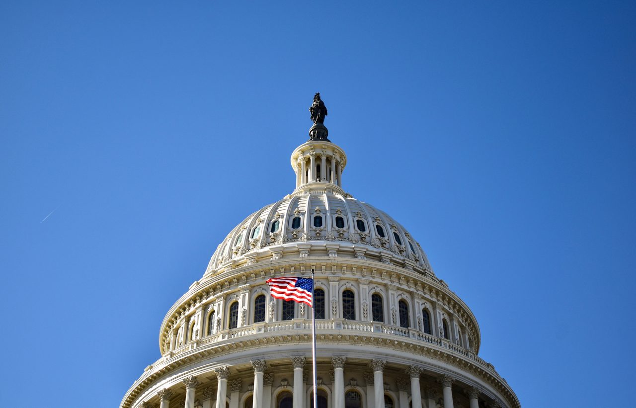 Dome of the U.S. Capitol and a U.S. flag waving