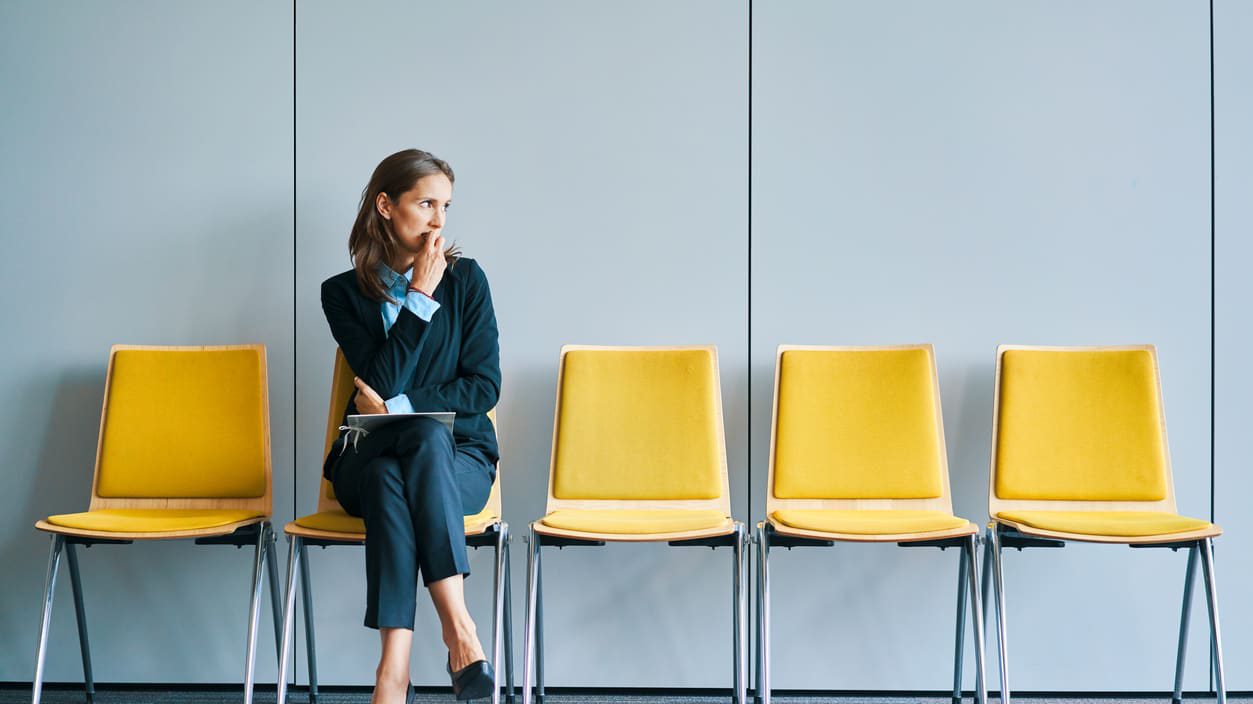 A woman sitting in a row of yellow chairs.