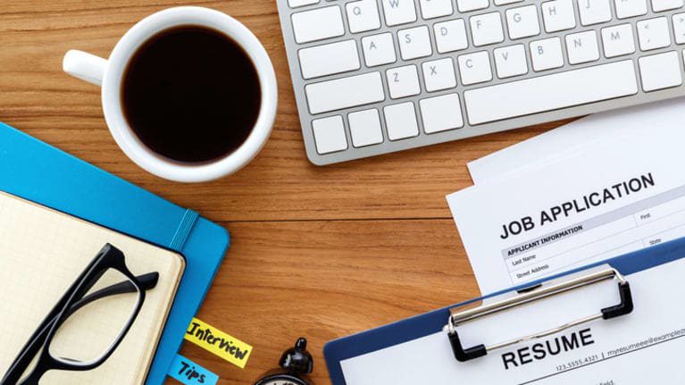 A job application on a desk with a cup of coffee.