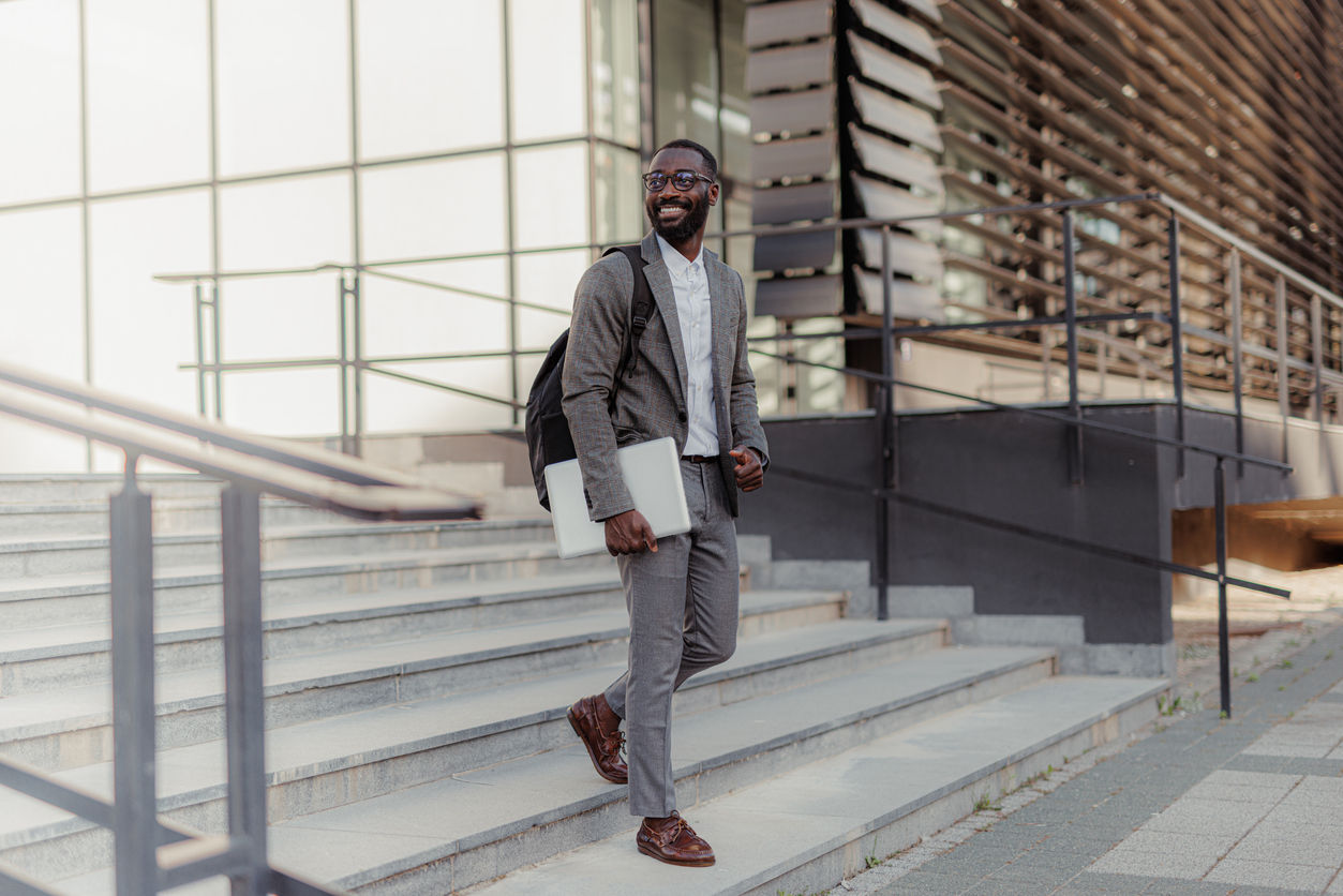 A young professional, walking down stairs outside a modern office building.