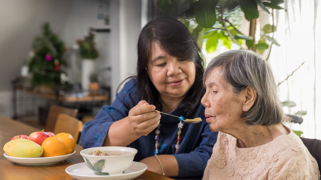 Woman helping elderly person eat