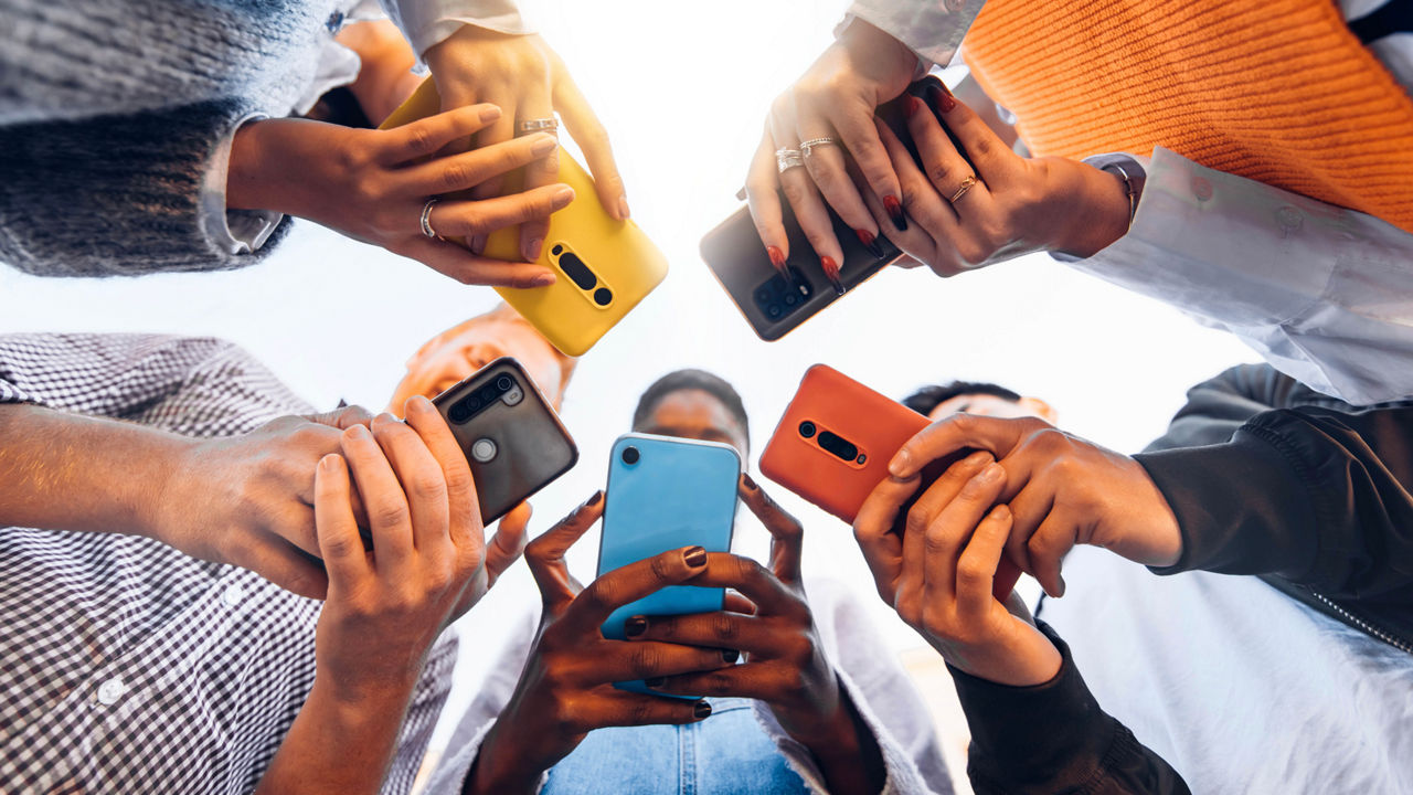 A group of people using cellphones close together outside