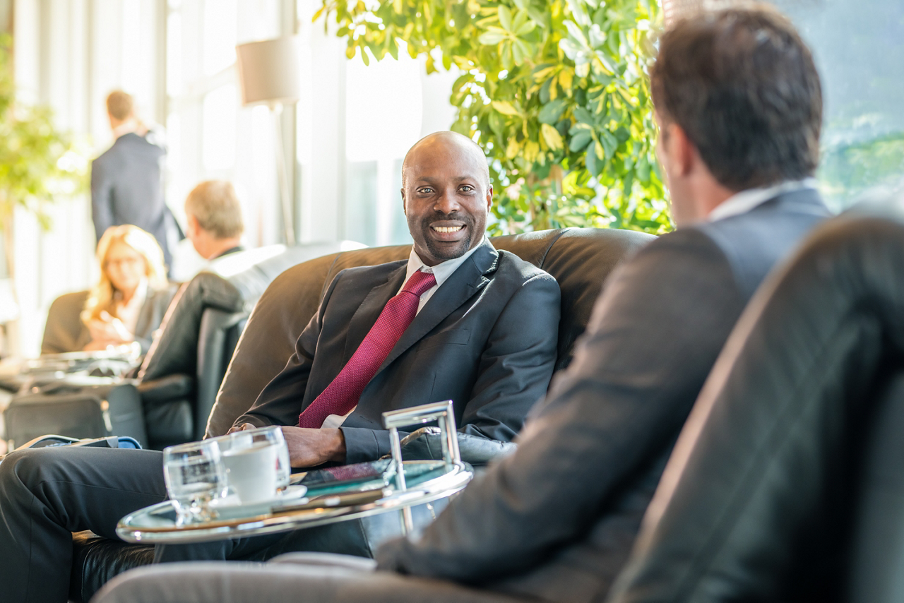 Businessmen sitting on chair at airport departure area.