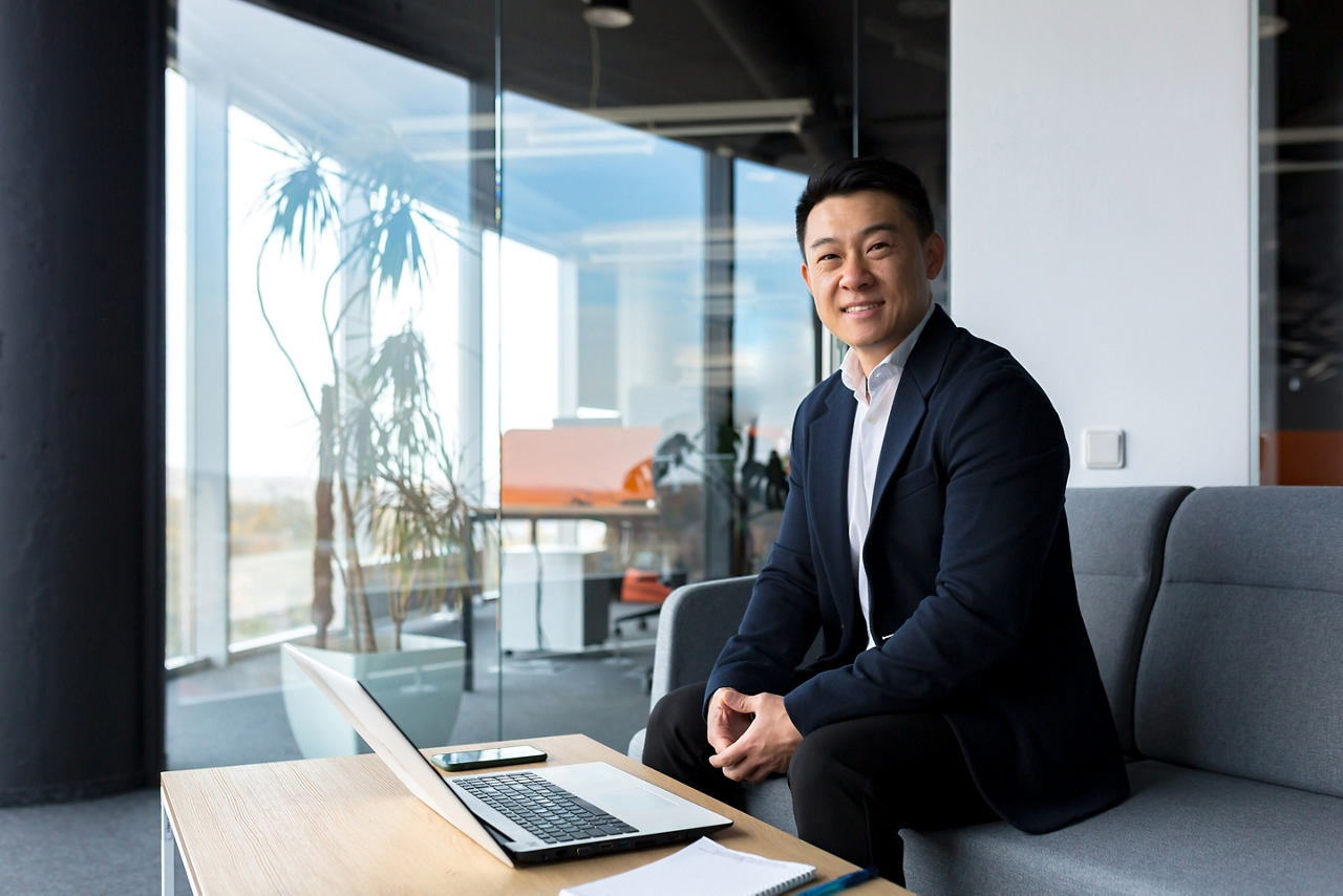 Successful and happy asian man working online remotely on laptop smiling happy with plan and task