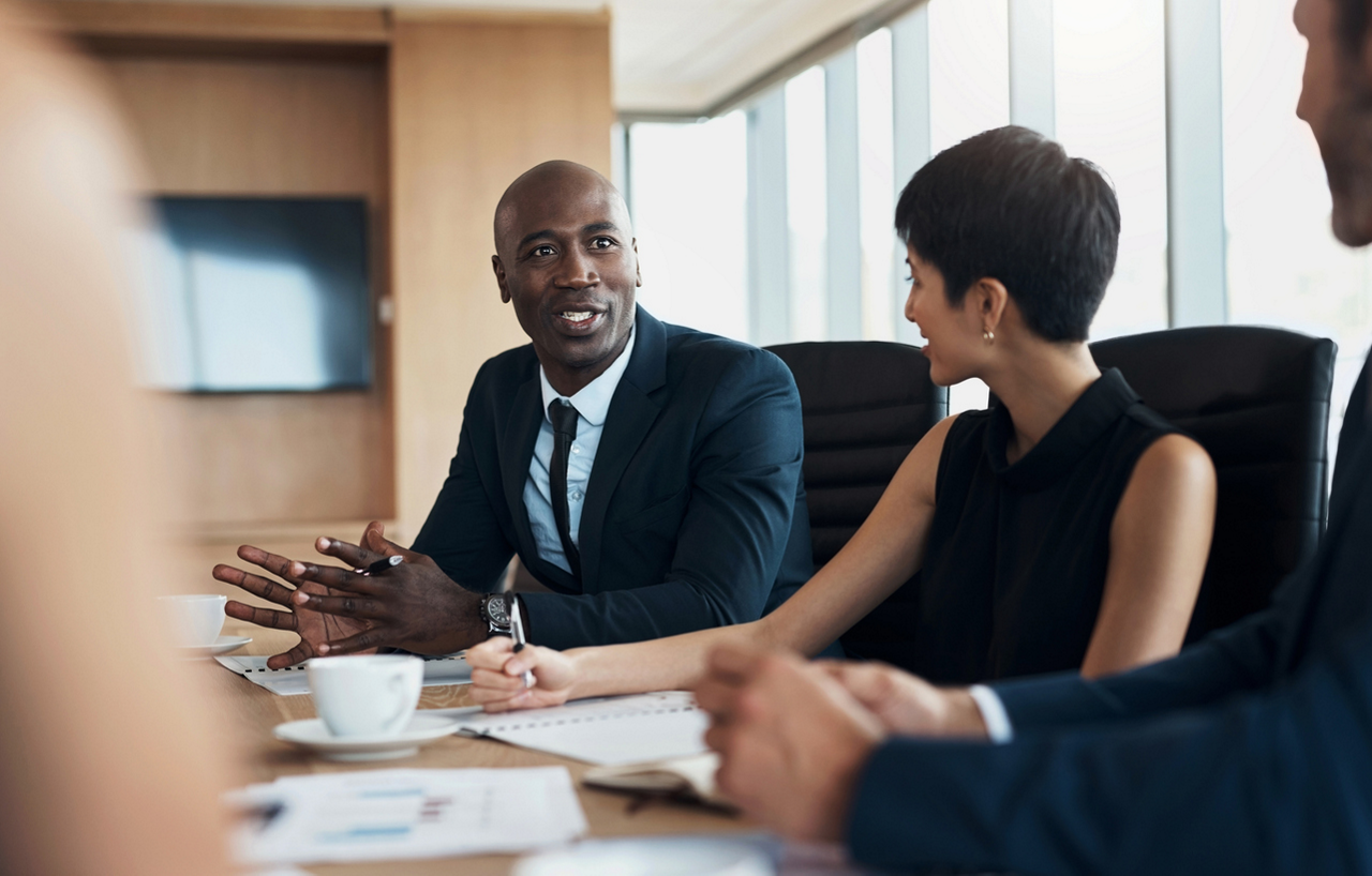 Business meeting, speaking and black man with discussion, planning and corporate proposal, staff update and leadership. Professional people in conference room talking, listening and career strategy