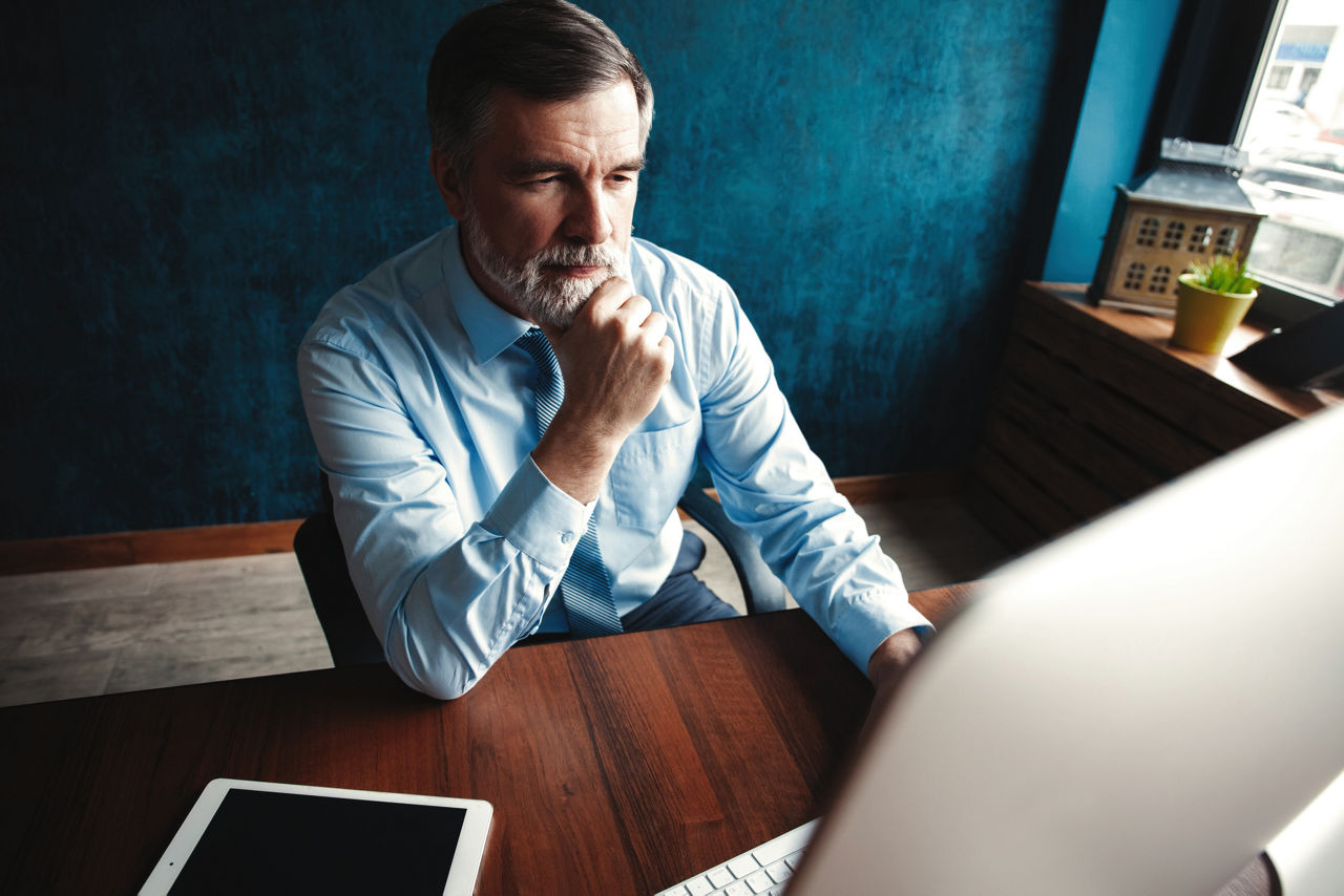 Mature Businessman Working On Computer In Modern Office