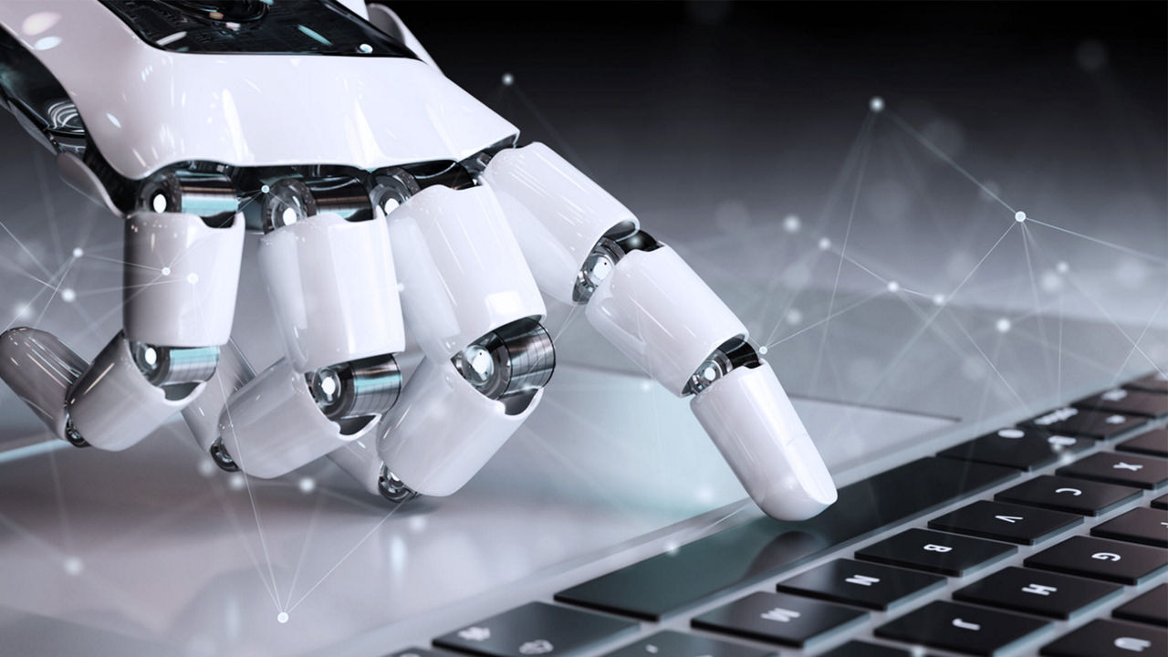 A robotic hand is typing on a laptop.