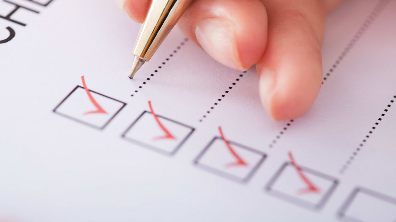 A person filling out a checklist with a pen.