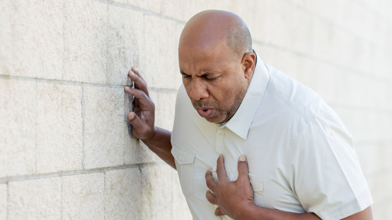 A man with a chest pain leaning against a wall.