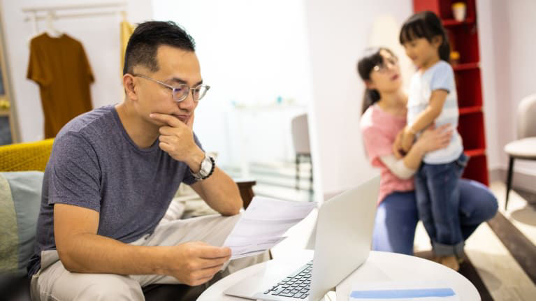 A man and woman sitting on a couch with a laptop in front of them.