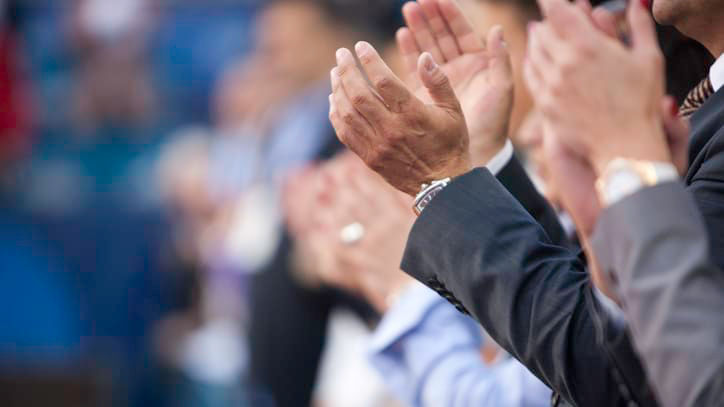 A group of people clapping at an event.