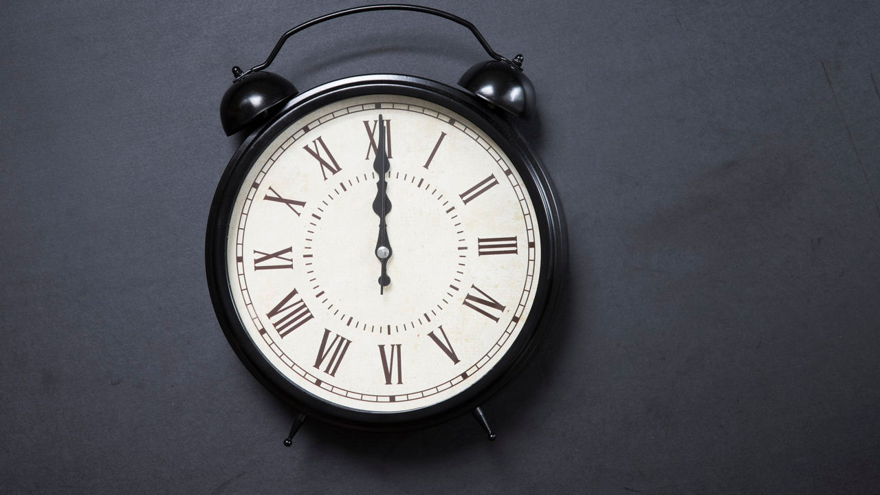 A black alarm clock on a dark background.