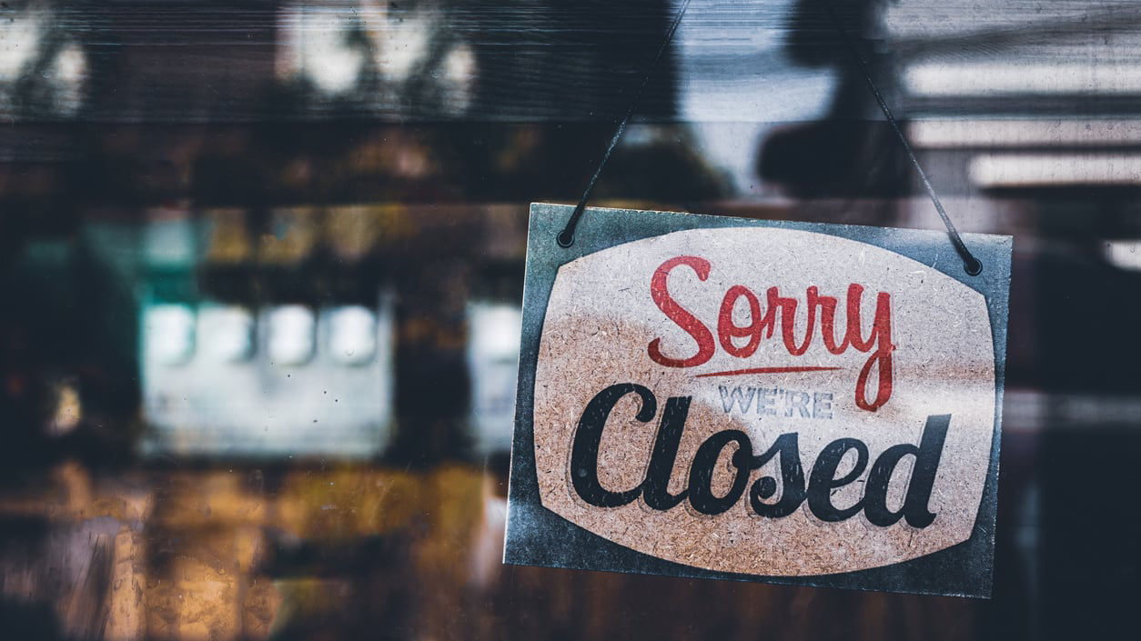 A sign that says sorry we're closed hanging on a window.