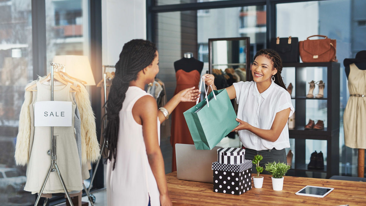 Two women in a clothing store holding shopping bags.