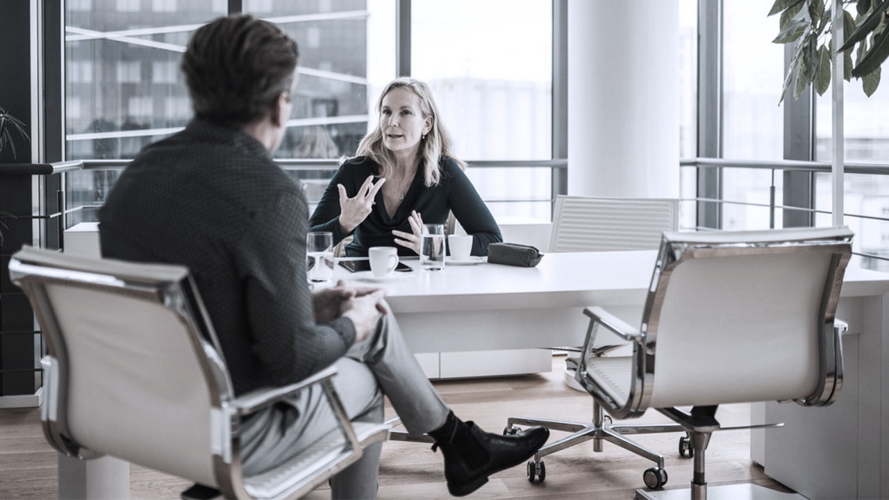 Image of two business leaders at a desk in a coaching conversation.