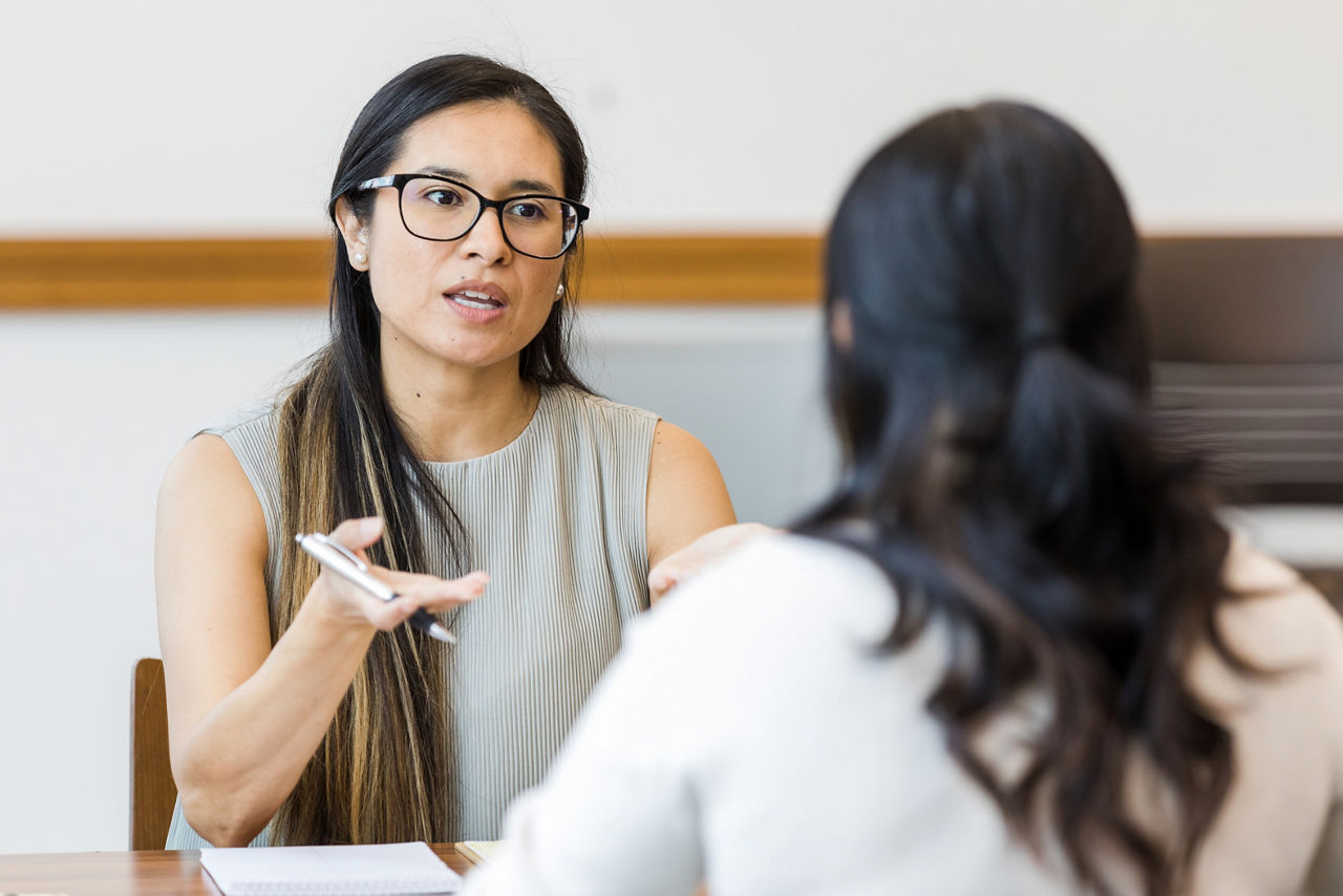 The mental health therapist sits with her female client in the conference room to talk about her work struggles.