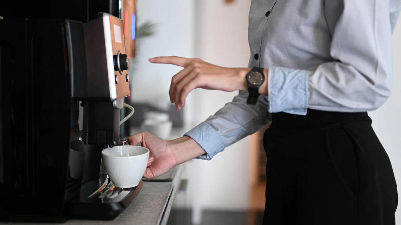 close up of woman getting coffee from machine in an office