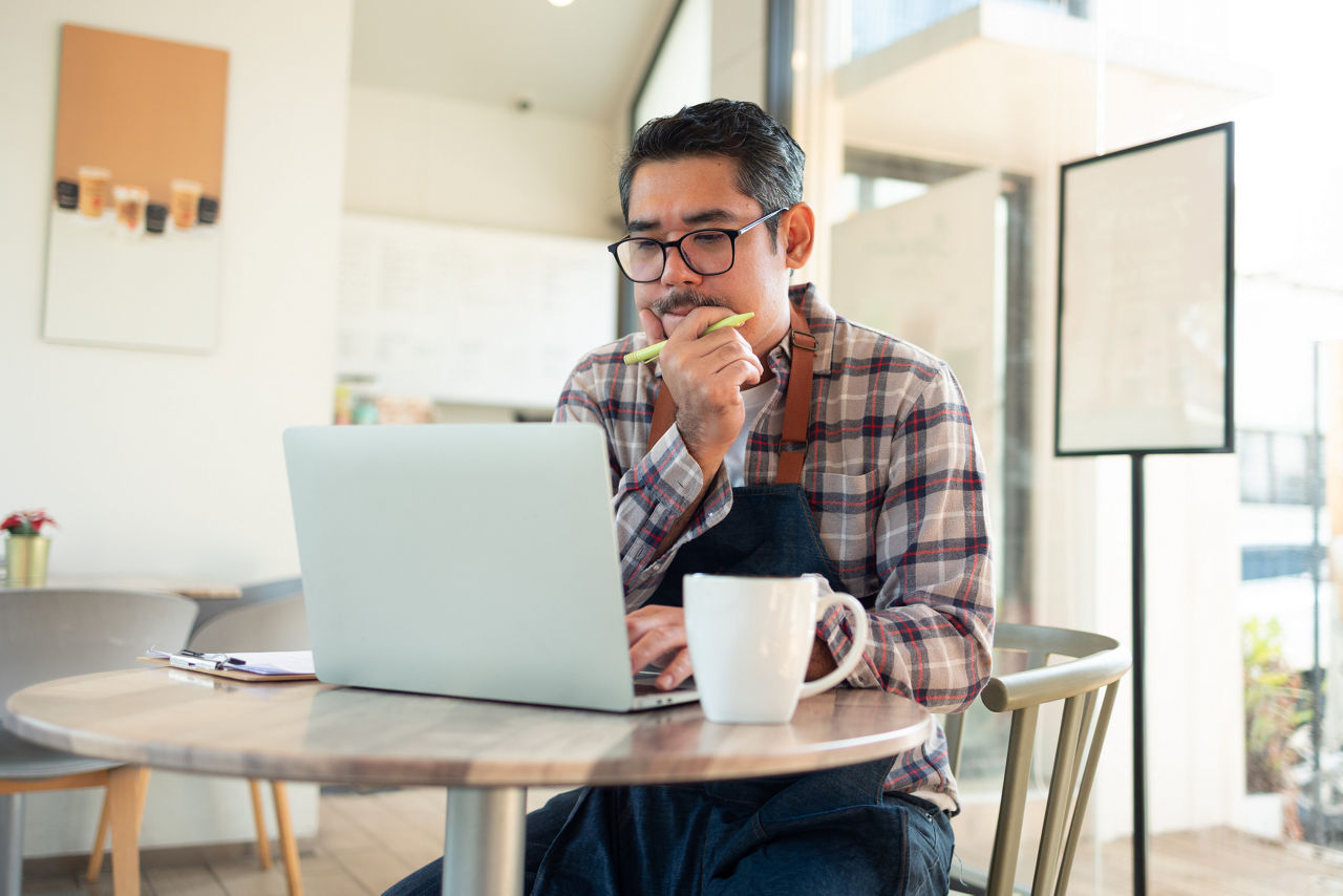 Entrepreneur Discussing Business strategy in a Modern Coffee Shop.Happy   barista using laptop for take order from customer.