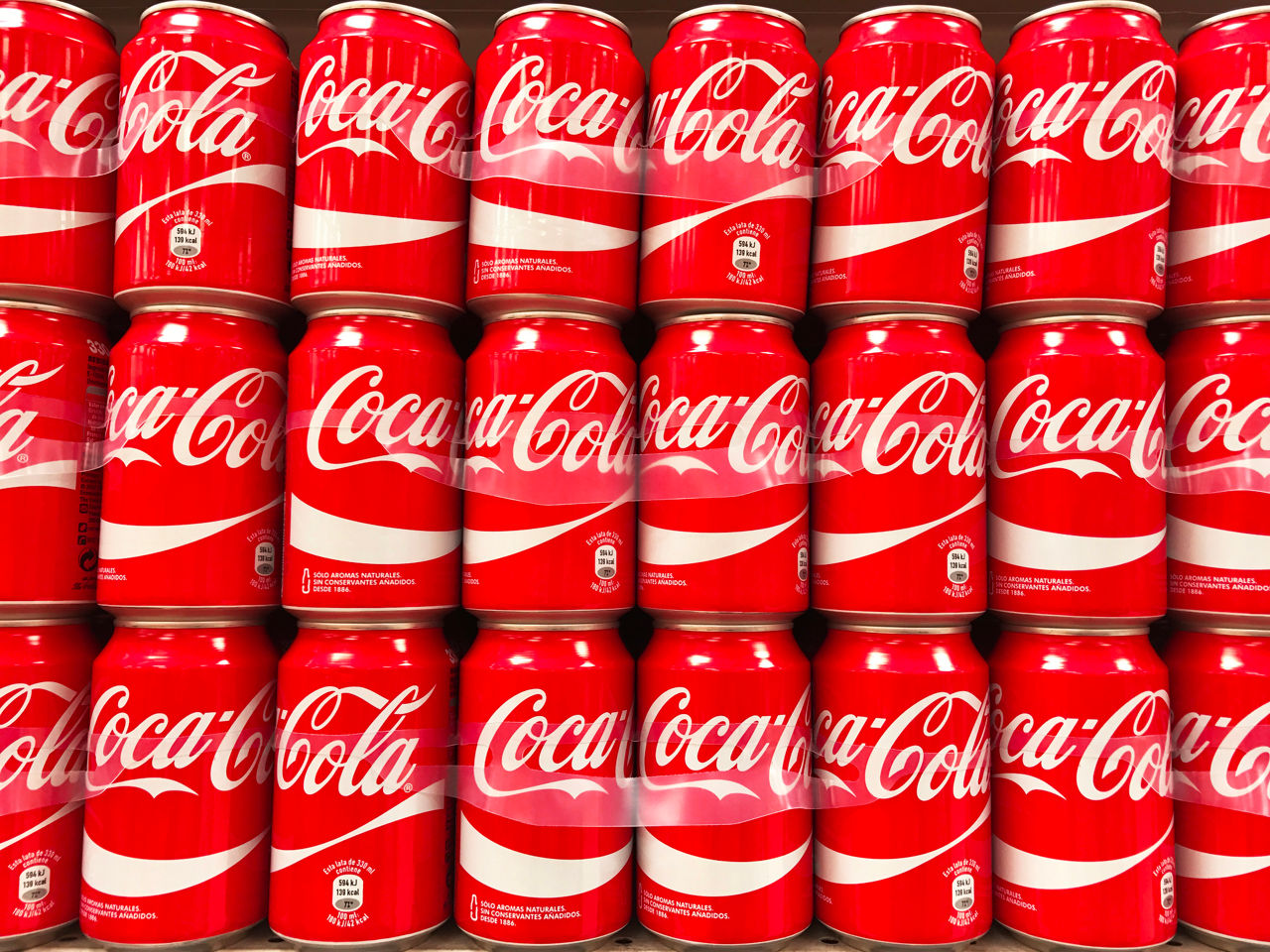 A large group of Coca-Cola red cans stacked in a supermarket in Spain.