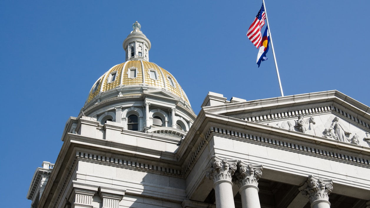 An american flag flies over the capitol building in denver, colorado.