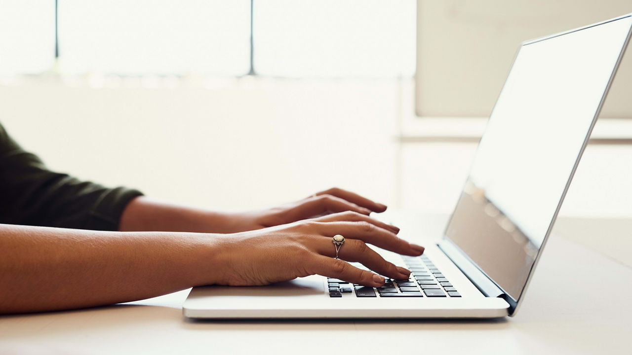 A woman typing on a laptop in an office.