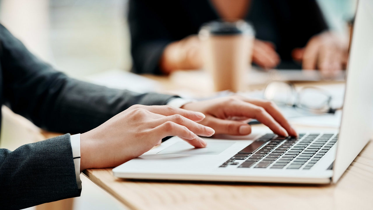 A group of business people typing on a laptop.
