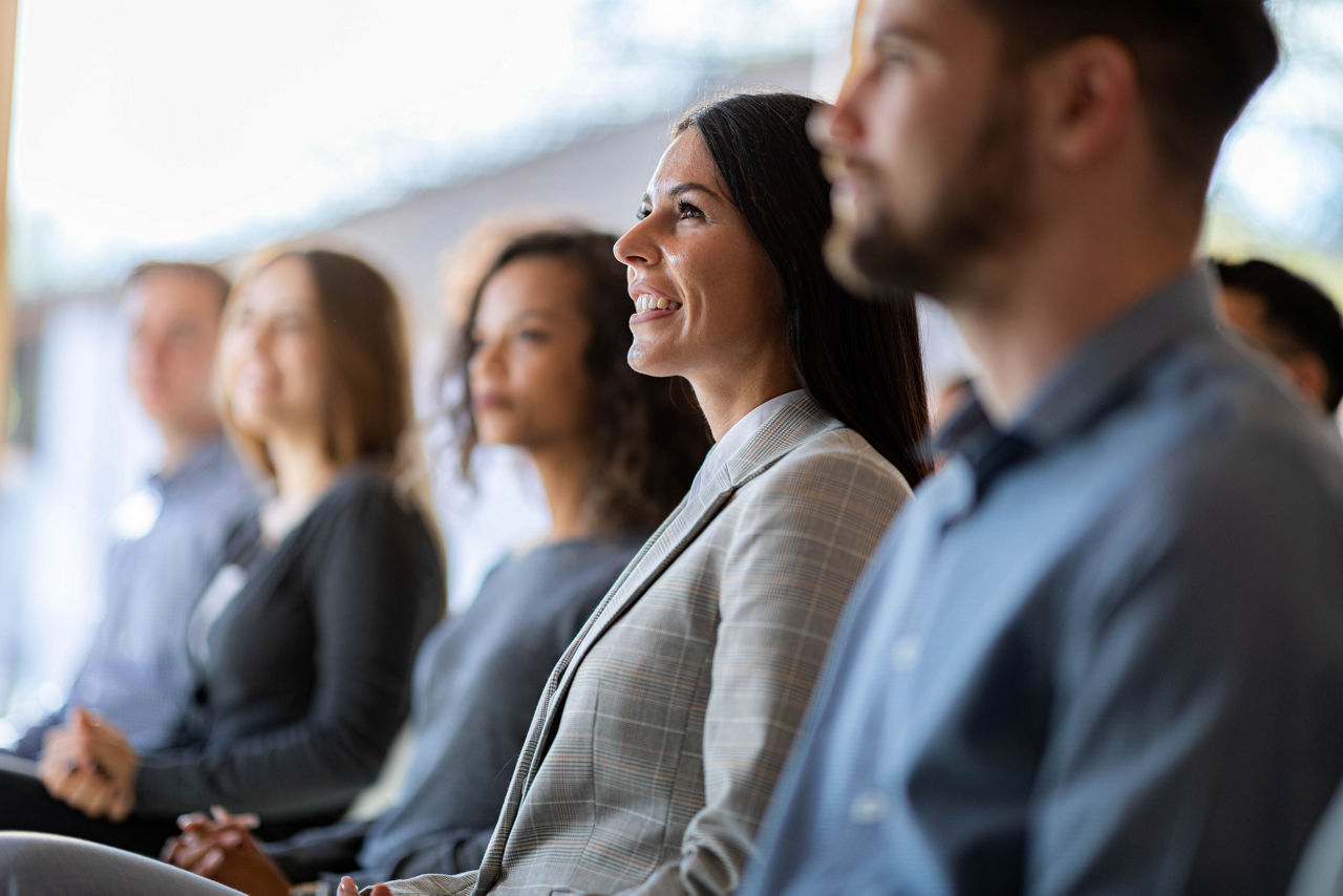 Happy female entrepreneur and her colleagues attending an education event in board room.