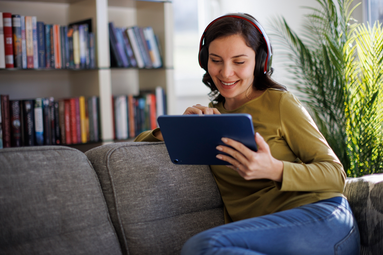 Smiling woman relaxing with digital tablet on couch at home
