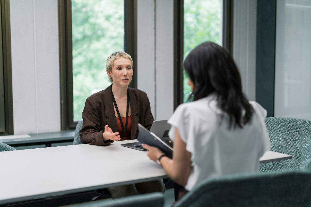 Two businesswomen have a discussion in a private office.