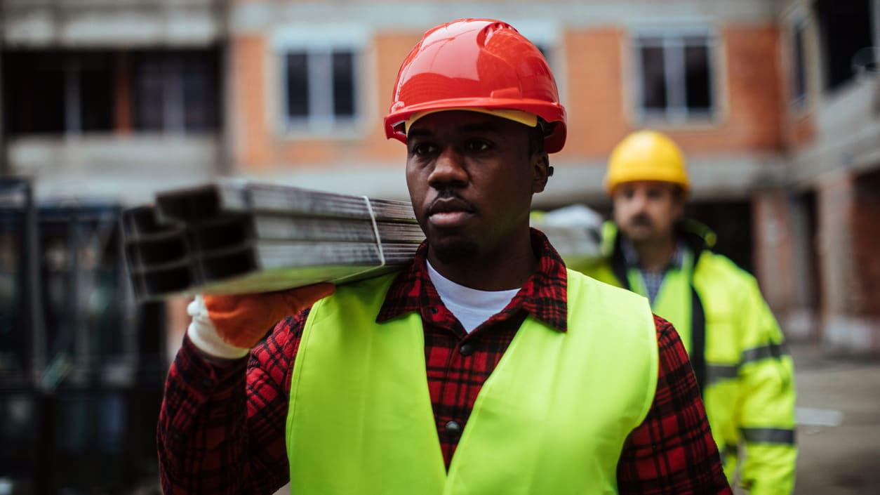 Two construction workers carrying a piece of metal.
