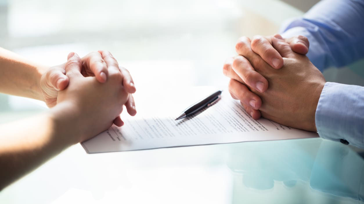 A man and woman signing a contract at a table.