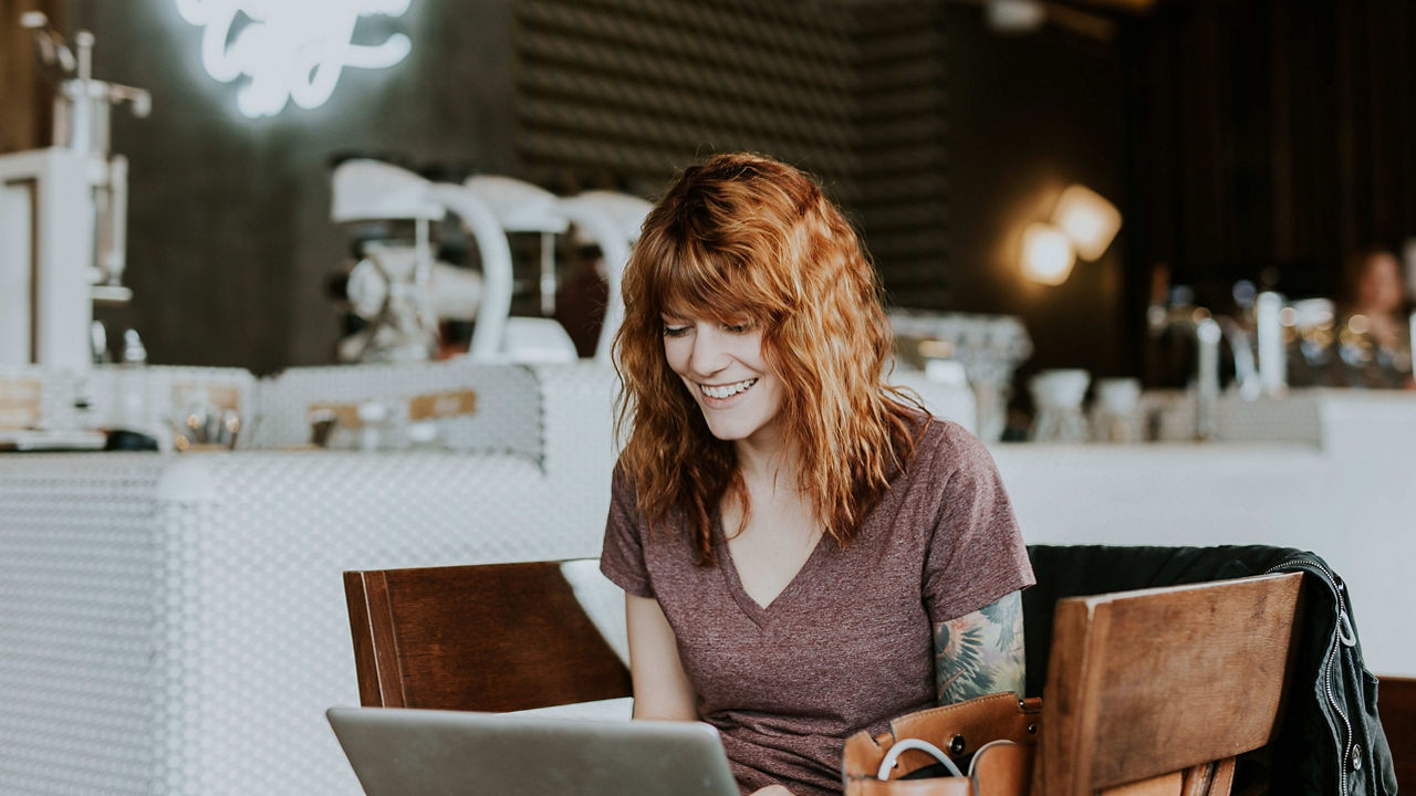 Woman sits with her computer at a cafe