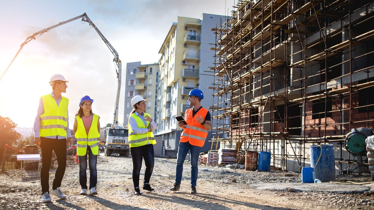 Three construction workers standing in front of a construction site.