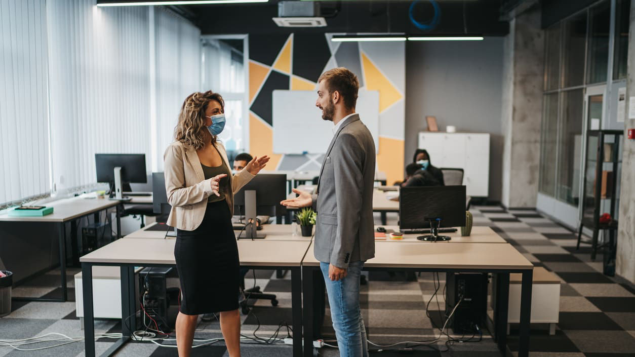 A man and woman wearing face masks in an office.