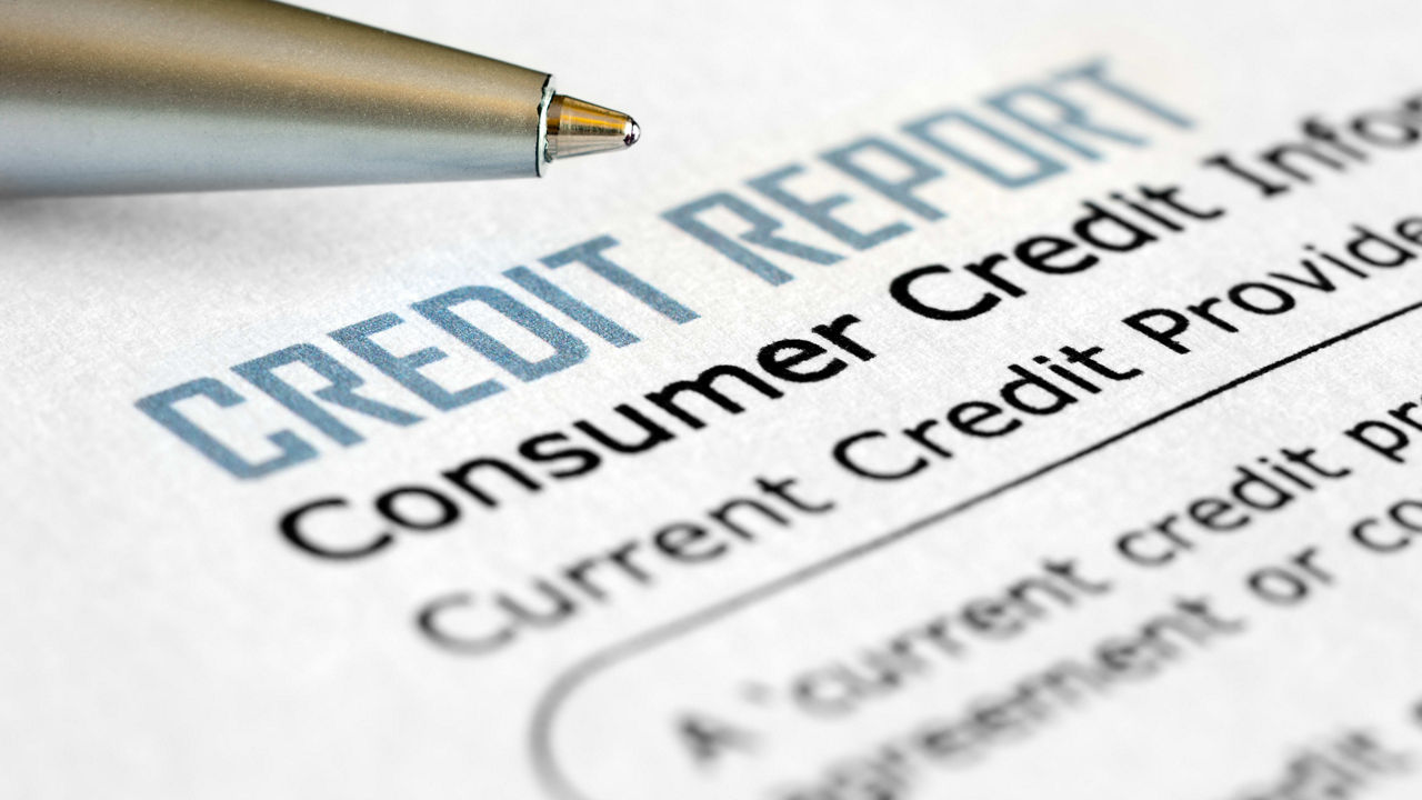 A pen sits on top of a credit report.