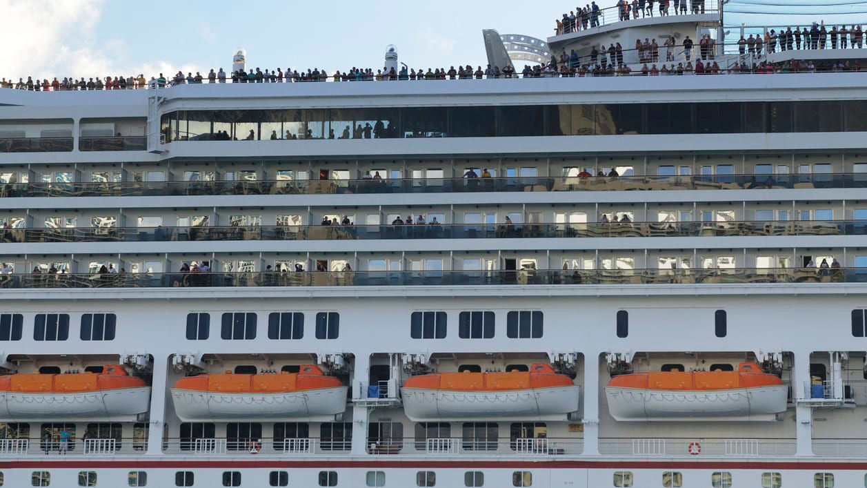 People are standing on the top of a cruise ship.