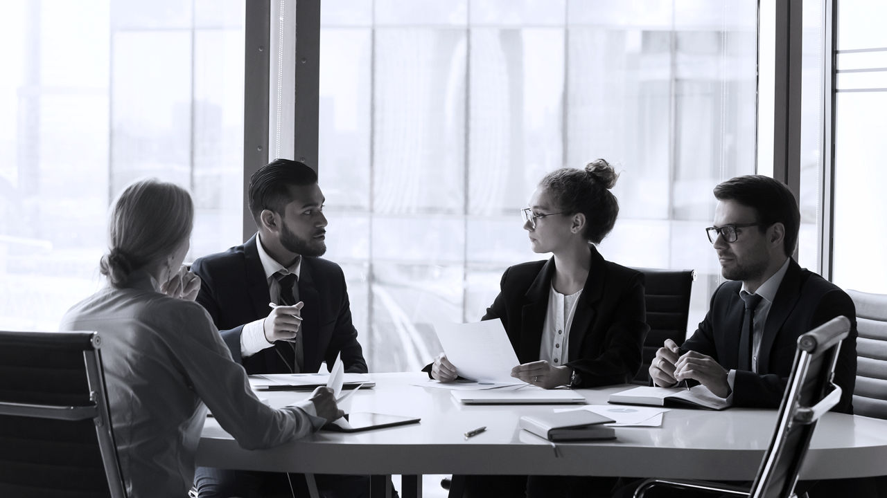 Four people sitting at a table talking in office