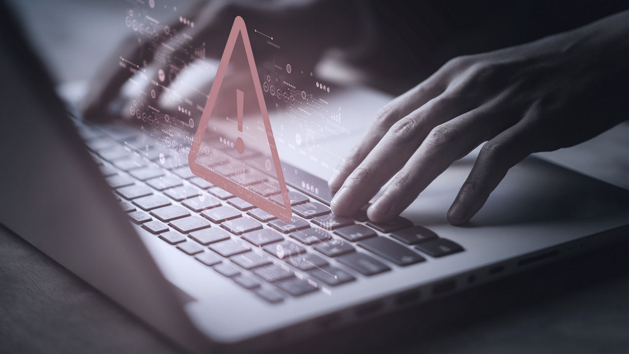 Image of hands typing on a laptop with error symbol over top.