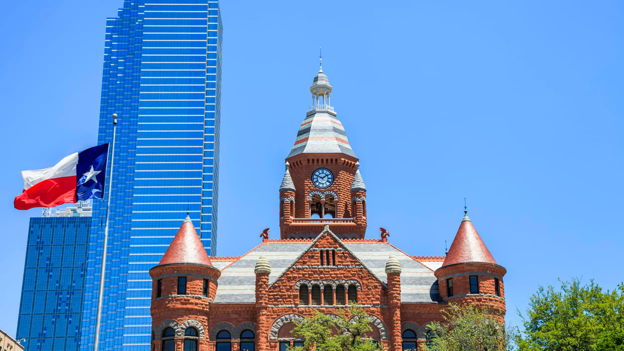 A building with a clock tower and a texas flag.