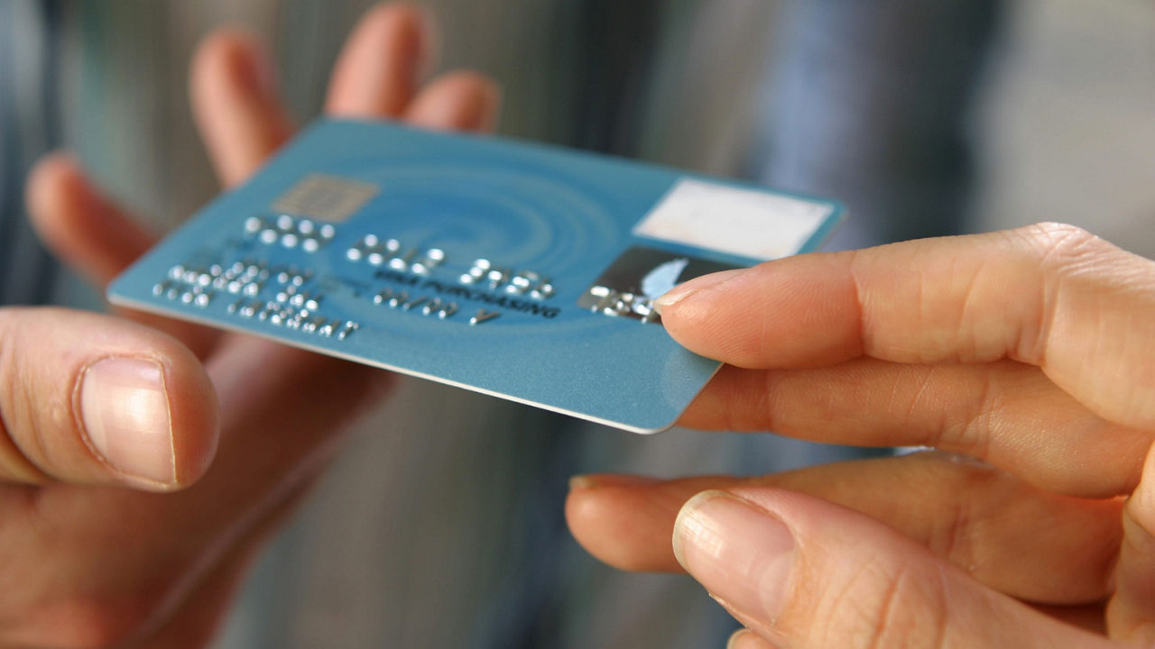 A person's hand holding a credit card.