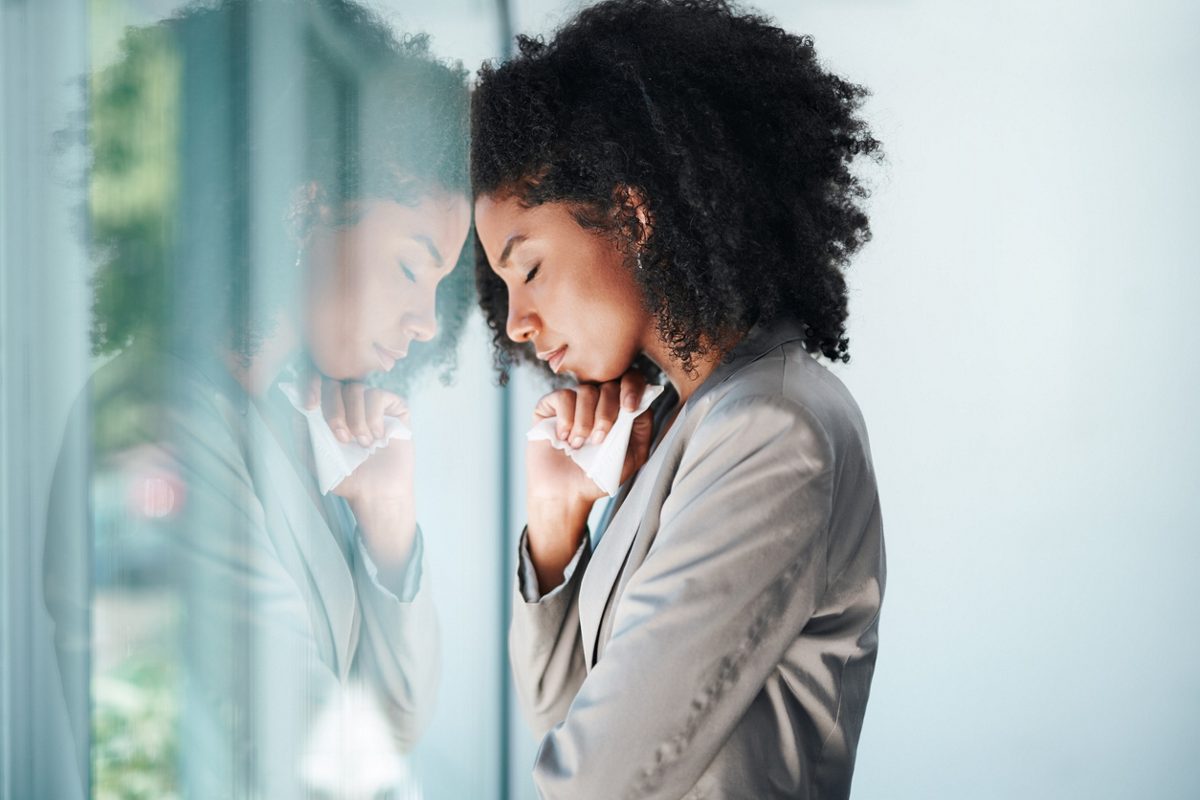 woman with hands on her temples stressed out behind her desk